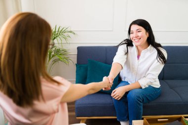 Warm and engaging female psychologist extends a handshake to her patient, initiating a supportive psychotherapy session for mental health and well-being