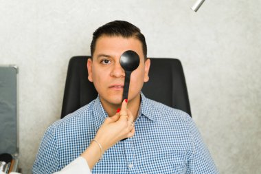 Hand of an ophthalmologist using occluder to assess patient's vision in a clinical setting, ensuring accurate evaluation of eye health and function clipart