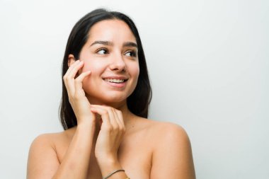 Işıl ışıl cildi olan sakin Latin bir kadın spa tedavisi sırasında gülümsüyor, profesyonel bir ortamda doğal güzellik ve refahı temsil ediyor.