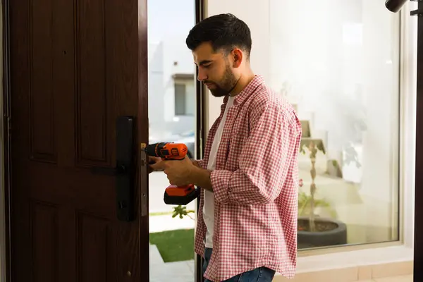 stock image Skilled handyman expertly fitting a strong door lock with a screwdriver, guaranteeing the protection and peace of mind for a home