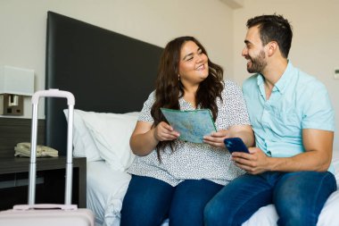 Haritada yol tarifi ararken birbirlerine bakan mutlu çift ve otel odalarında akıllı telefon uygulaması kullanıyorlar.