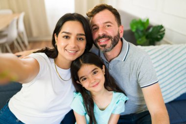 Gülümseyen aile evlerinde oturma odasındaki kanepede dinlenirken selfie çekiyor.