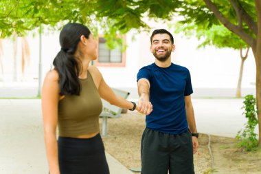 Spor kıyafetleri içinde genç ve mutlu bir İspanyol çift. El ele tutuşup, spor yaparken gülümsüyorlar.