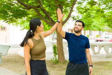 Neşeli atletik çift dışarıda parkta çalıştıktan sonra bir beşlik çakarken mutlu ve tatmin olmuş hissediyorlar.