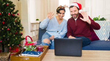 Noel arifesinde aile ve arkadaşlara el sallayan bir çift.