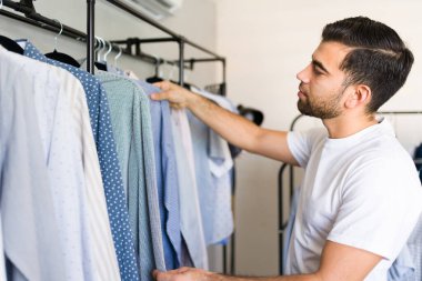 Dolabından tişört seçen bir adam gündelik ama modaya uygun tarzını yansıtıyor. Evde kişisel bir anı yakalamak.