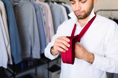 Bir iş adamının kırmızı kravatını gardırobunun önünde bağlayıp sabah işe hazırlanması.