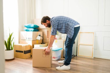 Adam yeni bir daireye taşınırken ağır bir kutuyu kaldırıyor. Eşyaları yerleştirme ve yerleştirme zorluklarıyla yüzleşiyor. Sırt ağrısı ve yalnızlığa rağmen rahat bir yer yaratmaya kararlı.