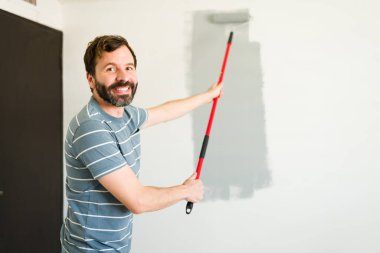 Tamirat projesi sırasında duvarları griye boyarken gülümsüyor.