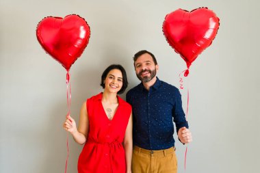 Sevimli bir çift ellerinde kalp şeklinde balonlar, sevgililer gününü birlikte kutluyorlar.