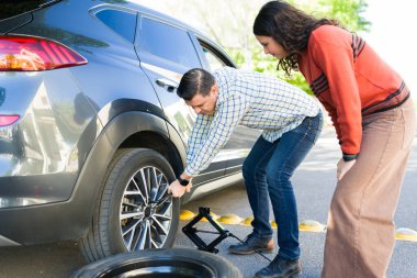 Baba genç kızına lastik değiştirmeyi öğretiyor, yol kenarında birlikte çalışıyoruz.