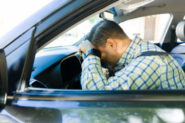 Stresli adam, yorucu bir iş gününden sonra yorgun ve bitkin bir halde arabasının içinde otururken direksiyonda dinleniyor.