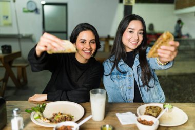 Two friends enjoying delicious tacos and beverages at a traditional mexican taqueria, showcasing the vibrant flavors of mexican cuisine clipart