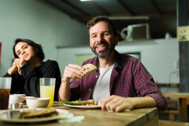 Cheerful man enjoying delicious tacos at a taqueria, sharing a meal with friends in a casual and authentic mexican setting clipart