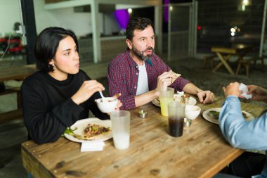 Group of friends eating tacos and having drinks together at a taqueria, enjoying a casual meal and conversation clipart