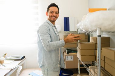 Küçük işletmesini denetleyen İspanyol adamın portresi, ofis deposunda karton paketler düzenlemek.