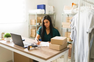 İspanyol kadın girişimci siparişleri yönetir ve paketlerini küçük giyim mağazasında nakliye için hazırlar.