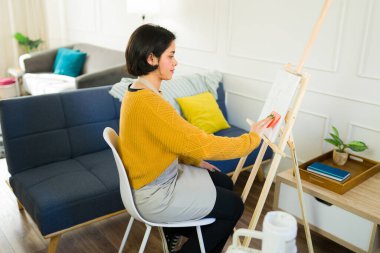 Tuvale süngerle resim yapan yaratıcı kadın oturma odasındaki sanat eserlerine doku ekliyor.