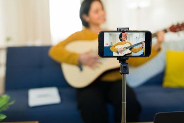 İspanyol kadın evinde canlı bir müzik videosu kaydediyor, akustik gitarını tıngırdatıyor ve o anı akıllı telefonuyla yakalıyor.