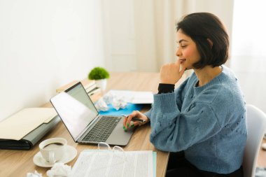 Kadın yazar evde dizüstü bilgisayar kullanarak yeni bir kitap üzerinde çalışıyor, bir fincan kahvenin tadını çıkarıyor ve hikaye dizisini düşünüyor.