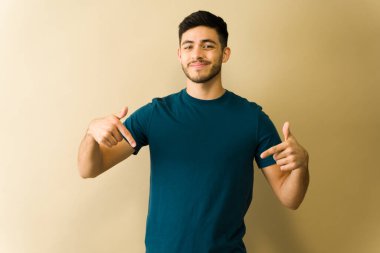 Her iki işaret parmağıyla fotokopi alanına bakan gülümseyen genç bir adamın portresi.