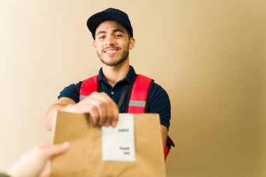 Mutlu teslimatçı, evinde memnun bir müşteriye fatura ile birlikte bir kesekağıdını teslim ederken gülümsüyor.