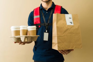 Kurye, termal sırt çantası ve üniforma giyerken yiyecek ve içecek getiriyor. Müşterilere hızlı servis sağlıyor.