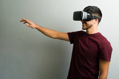 VR kulaklık takan ve sanal çevreyle etkileşim halinde olan genç bir adamın profili.