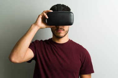 Adam kendini büyüleyici bir metaevren simülasyonuna daldırıp yeni dijital diyarlar ve deneyimler keşfederken bir VR kulaklığını ayarlıyor.