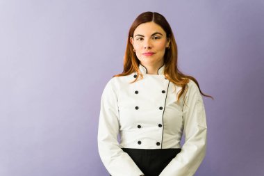 Siyah düğmeli beyaz üniformalı güzel bir şef mor arka planda duruyor.