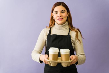 Kahve dükkanında çalışan arkadaş canlısı garson iki sıcak içecek taşıyor ve harika bir müşteri hizmeti sunuyor.