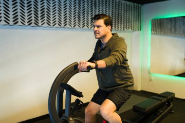 Orta yaşlı bir adam modern fitness ekipmanları kullanıyor. Formunu ve refahını geliştirmeye odaklanıyor.