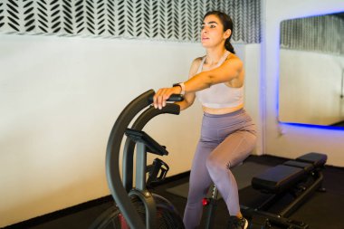 Sıkı hava bisikleti egzersizi yapan, beden eğitimi sırasında kardiyovasküler zindeliği güçlendiren ve enerjiyi yakan bir kadın.