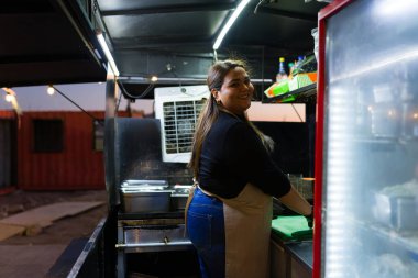Gülümseyen kadın şef canlı yemek kamyonunda lezzetli Meksika yemekleri hazırlıyor, akşam yemeklerinde yeteneklerini sergiliyor.