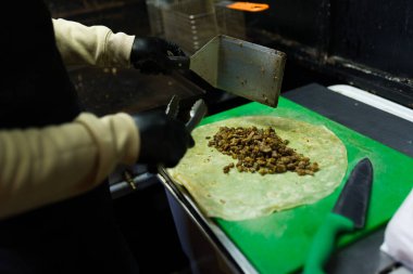 Dürüm hazırlamak, tortilla üzerine baharatlı et koymak spatula ve maşa kullanarak yemek kamyonu mutfağının içinde.