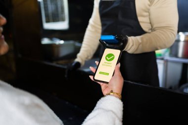 Milenyum ödemesi, renkli yemek kamyonundaki akıllı telefonla temas kurmadan, öğle yemeği sırasında dijital işlemleri yaparken gülümseyerek.