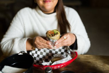 Bir müşterinin sokak yemekleri kamyonundan leziz bir burrito yiyip geleneksel Meksika yemeğinin tadını çıkarması.