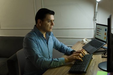 Akşamüstü saatlerinde yoğun bir şekilde profesyonel klavyeyle çalışmak, ev işyeri verimliliğini ön plana çıkaran aydınlatılmış dizüstü bilgisayar ekranı