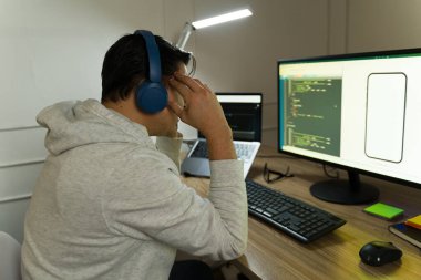 Uzman geliştirici, uzaktan bilgisayarla çalışırken kablosuz kulaklık takıyor.