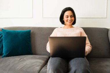 Uzaktan kumandalı işçi gülümsüyor, sanal profesyonel oturum sırasında dizüstü bilgisayar kullanırken koltukta dinleniyor.