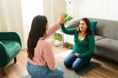 Destekleyici doğum koçu müstakbel anneye beşlik çakıyor, doğum öncesi konsültasyon sırasında pozitif enerji yayıyor, hamilelik sağlığı yolculuğunu kucaklıyor.