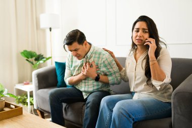 Latin kadın acil servisi ararken evde kalp krizi geçiren kocasını destekliyor.