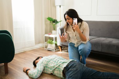 Üzgün İspanyol kadın ev zemininde baygın yatan kocasını gördükten sonra acil servisi arıyor.