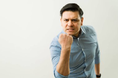 Profesyonel iş adamı yumruğunu sıkıyor, işyeri gerginliğini ve minimalist beyaz ortamda yoğun duygusal hüsranı ifade ediyor.