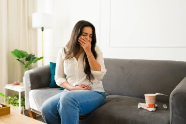 Karın ağrısı, hazır erişte yedikten sonra mide bulantısı, gıda zehirlenmesi belirtileri gösteren bir kadın.