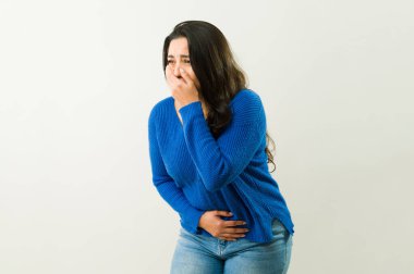 Hasta İspanyol kadın, mide bulantısı ve karın ağrısı hissederken ağzını ve burnunu kapatıyor.