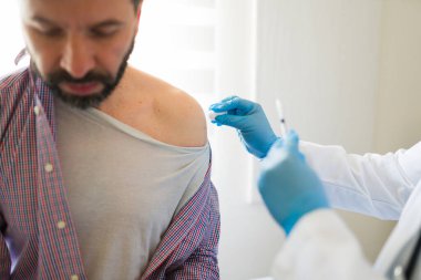 Tıbbi profesyonel dezenfekte hastanın omuz, steril enjeksiyon hazır klinik ortamında mavi tıbbi eldiven