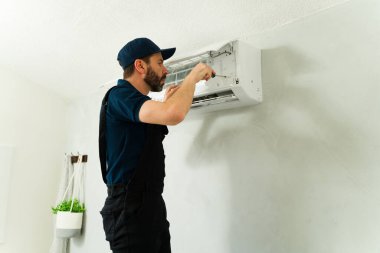 Hvac teknisyeni, bir konut evindeki servis çağrısı sırasında havalandırma ünitesini korumak için tornavida kullanıyor.