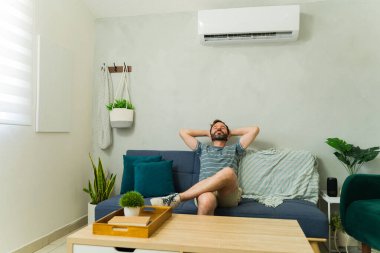 Rahat adam yaz sıcağında evdeki rahat bir kanepede dinlenirken serin klimanın keyfini çıkarıyor.