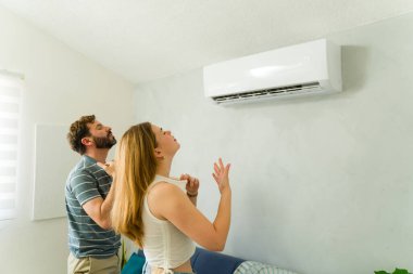Genç çift yaz sıcağında evlerinde mini bölme ünitesinden ferahlatıcı serin bir klimanın keyfini çıkarıyorlar.